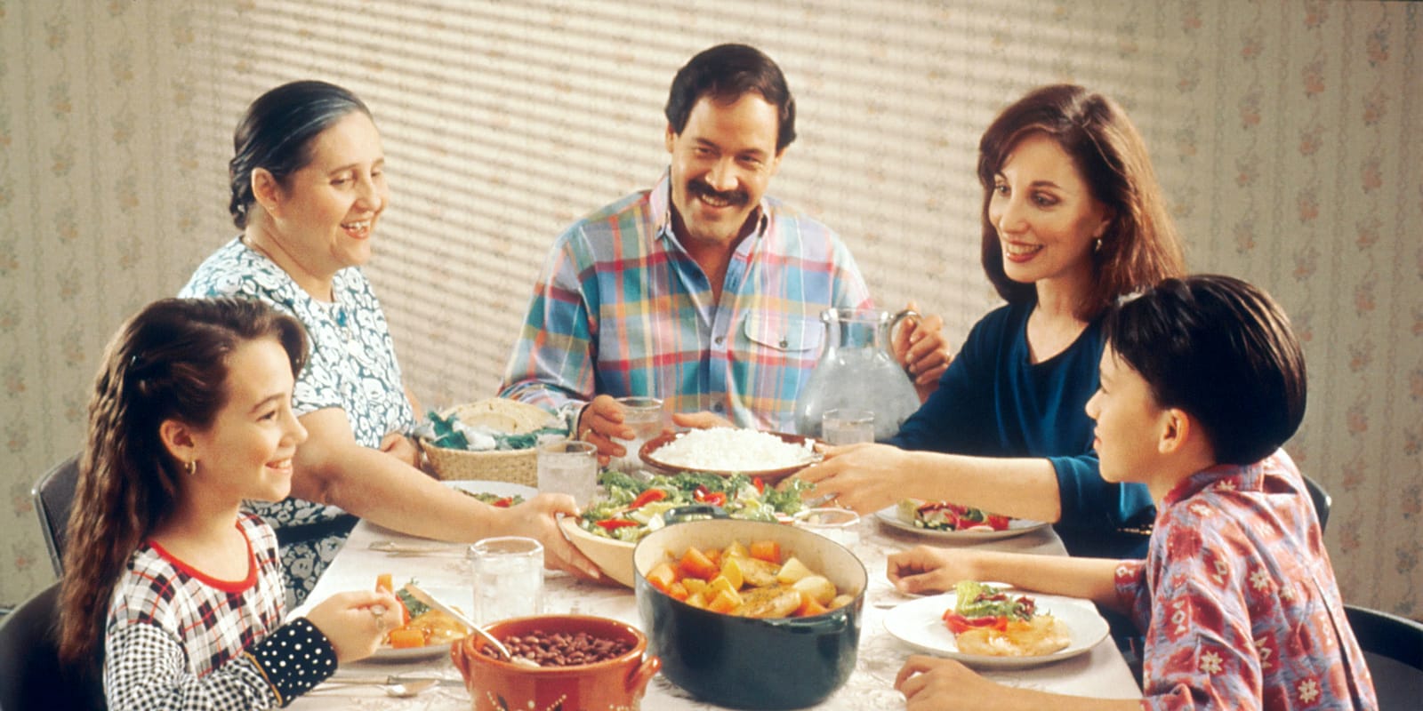 A family of three generations sharing a meal around a dinner table.